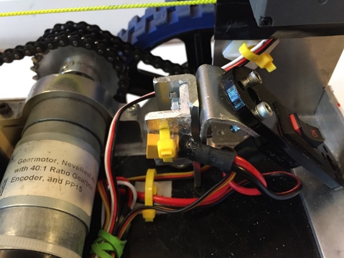 A flat REV Robotics battery pack mounted vertically in a 3D-printed holder secured with a Velcro strap.