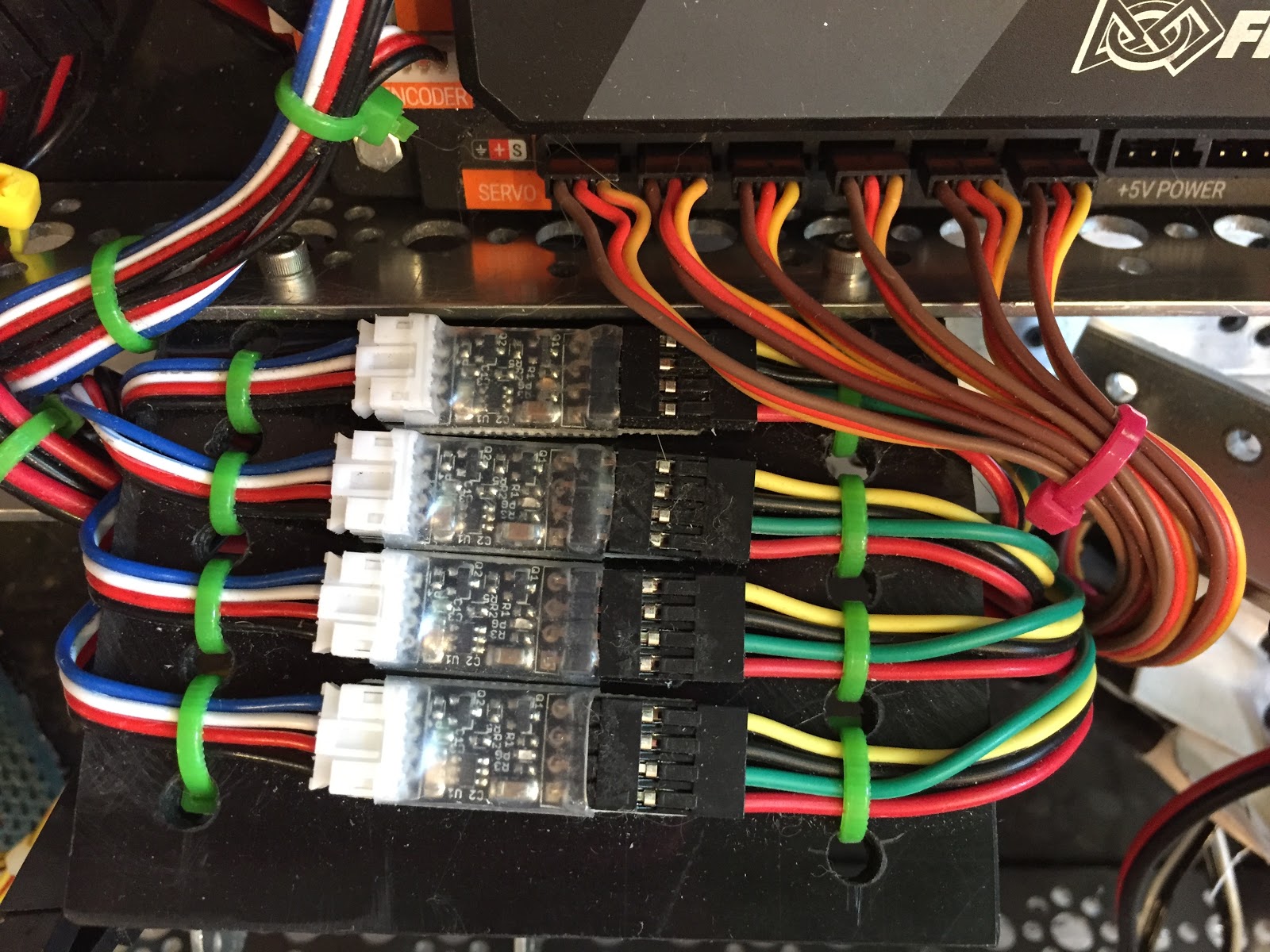 Four logic level shifter modules mounted on a plastic bracket, wired between motor encoders and a REV Expansion Hub.