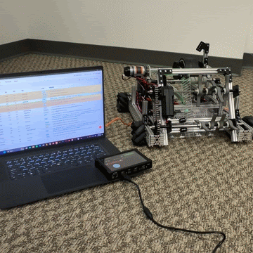 A laptop running REV Hardware Client 2 scrolls live log entries while a robot beside it runs.