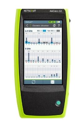 NetScout AirCheck G2 handheld tester displaying 2.4 GHz and 5 GHz channel utilization bar charts on its touchscreen.