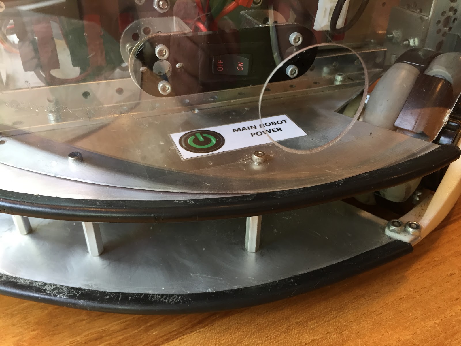A 12V power switch mounted inside a robot frame behind a clear side shield, labeled "Main Robot Power."