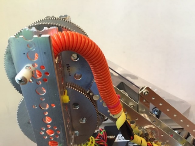 An orange spiral wire sheath protecting a bundle of wires as they cross a rotating arm joint.