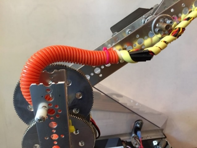 The same orange spiral wire sheath viewed from the side, anchored to the chassis with a zip tie.
