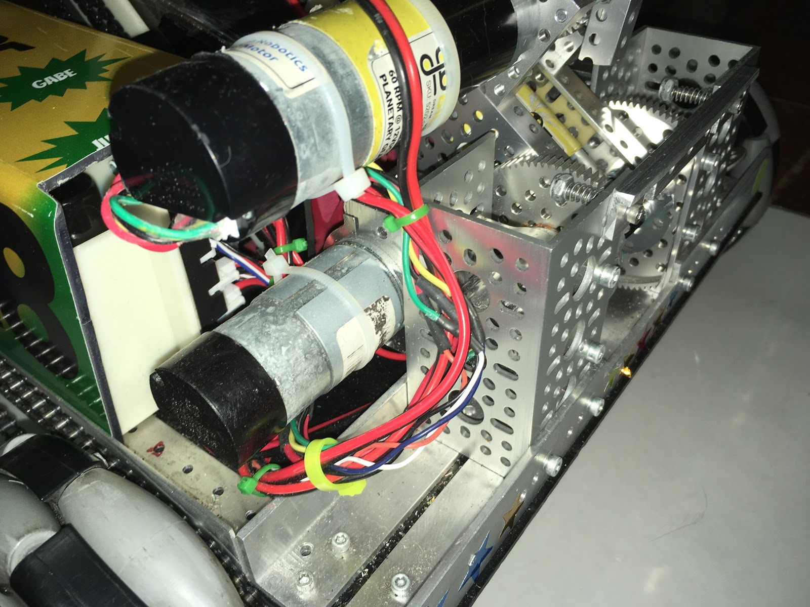 A gearmotor mounted on a movable arm with its power and encoder wires bundled and zip-tied into a service loop.